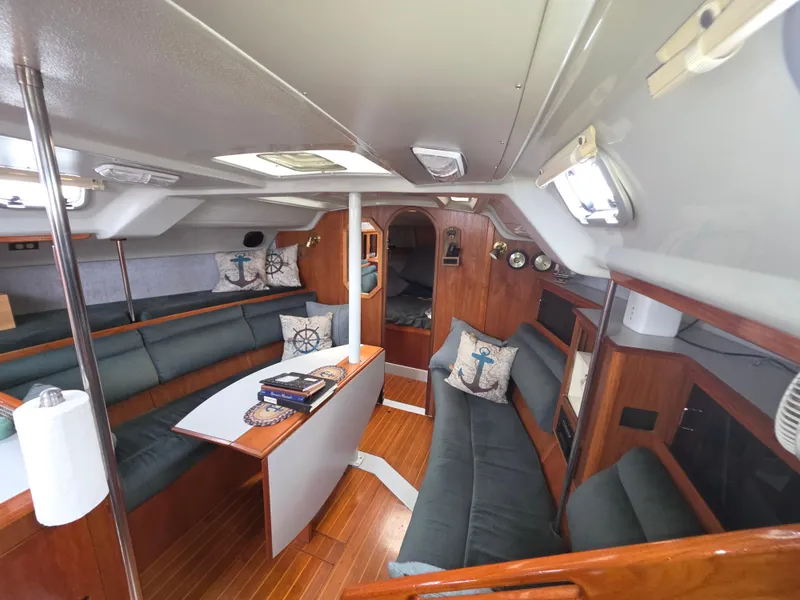 Slide: The Image of 1989 Hunter Legend 37 yacht interior with wooden flooring, cushioned seating, and nautical-themed decor. - 1