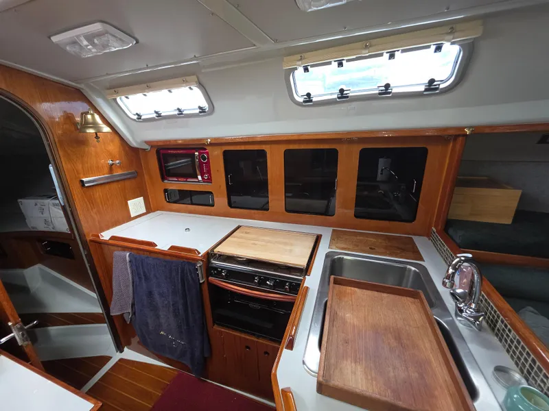 Slide: The Image of 1989 Hunter Legend 37 yacht interior with wooden cabinetry, kitchen sink, and appliances. - 10