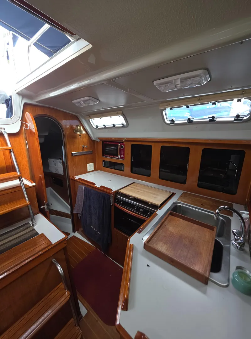 Slide: The Image of 1989 Hunter Legend 37 yacht interior with wooden cabinetry and compact kitchen area. - 2
