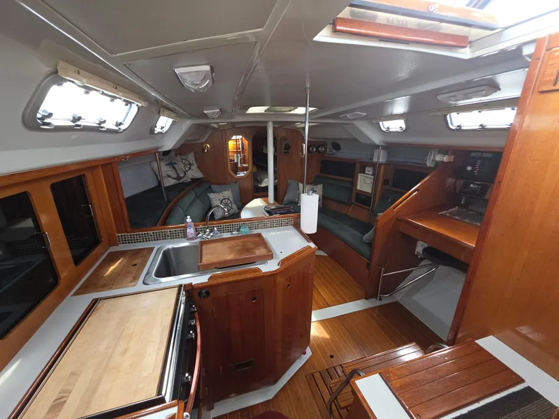 Slide: The Image of 1989 Hunter Legend 37 yacht interior with wood finish, kitchen, and seating area. - 9