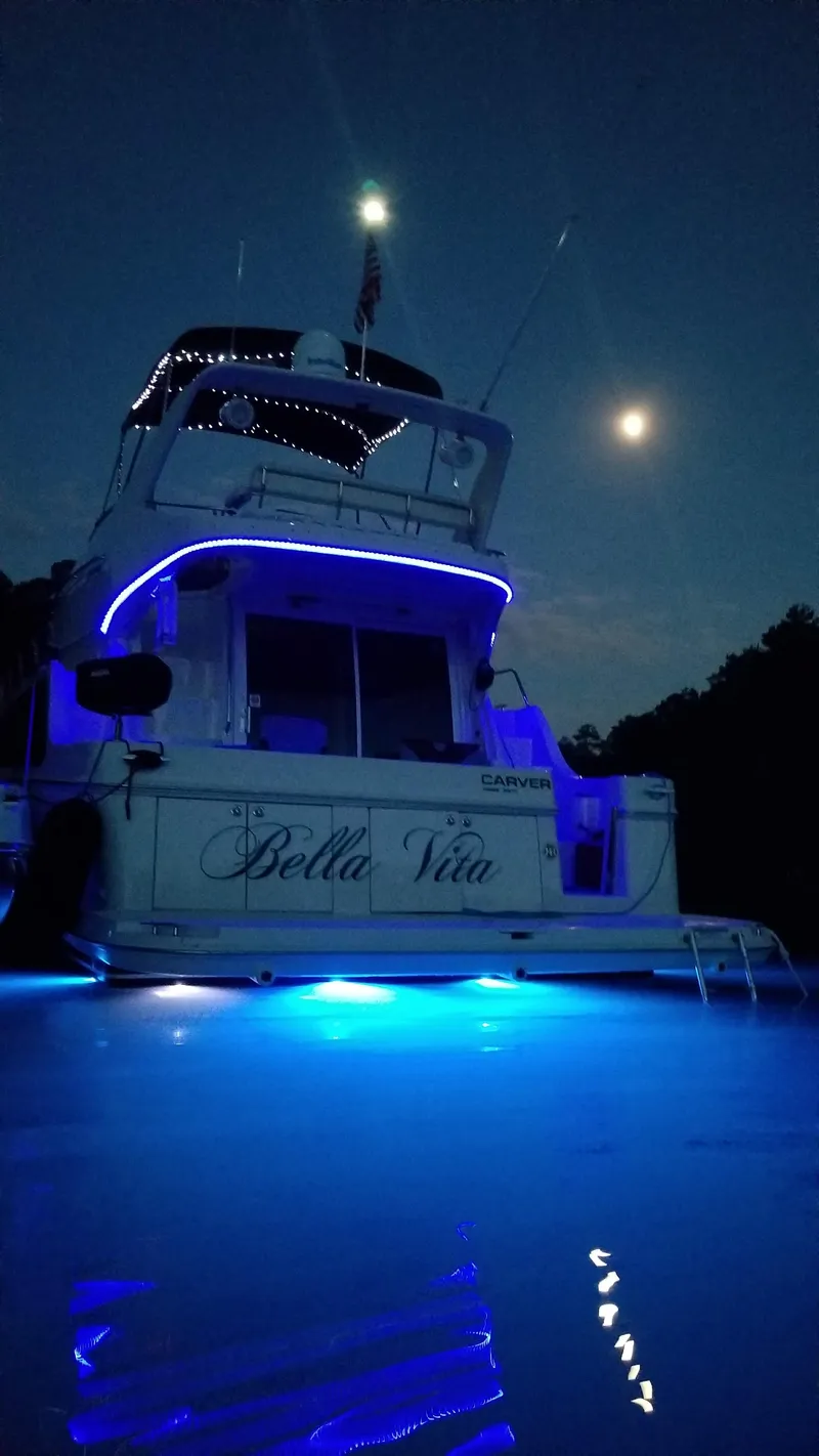 Slide: The Image of 2004 Carver 360 Sport Sedan yacht illuminated at night with blue lights under a moonlit sky. - 16