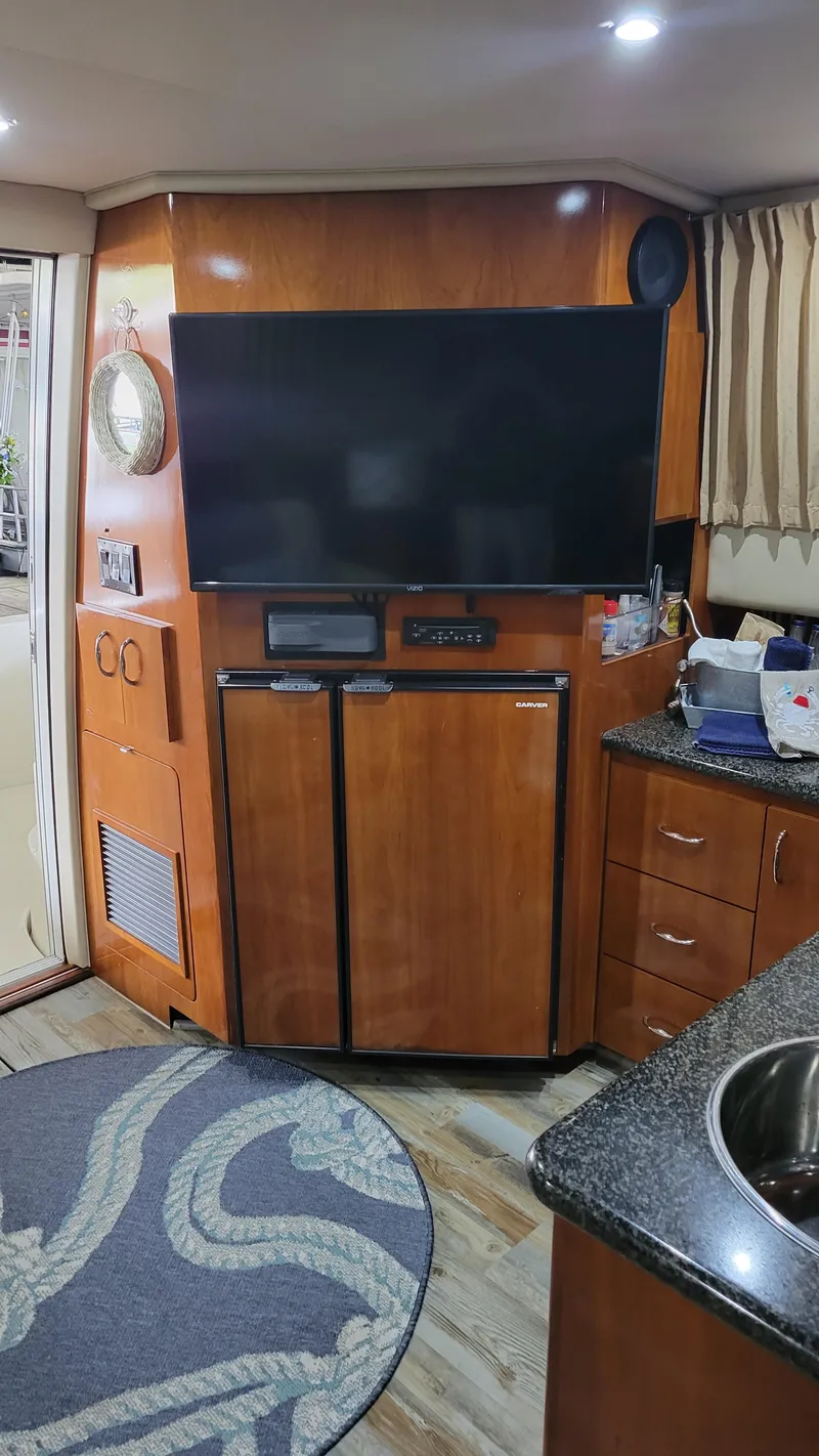 Slide: The Image of Interior of 2004 Carver 360 Sport Sedan with TV, fridge, and wooden cabinetry. - 28
