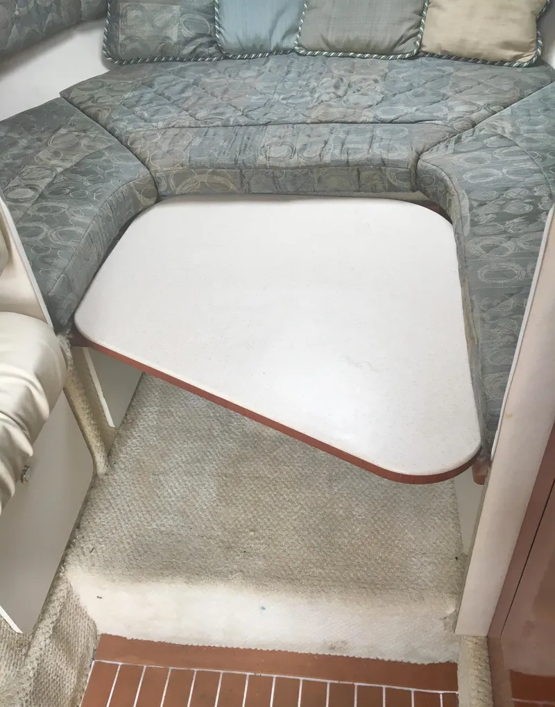 Slide: The Image of 2004 Sea Ray 280 Sundancer interior with cushioned seating and table. - 17