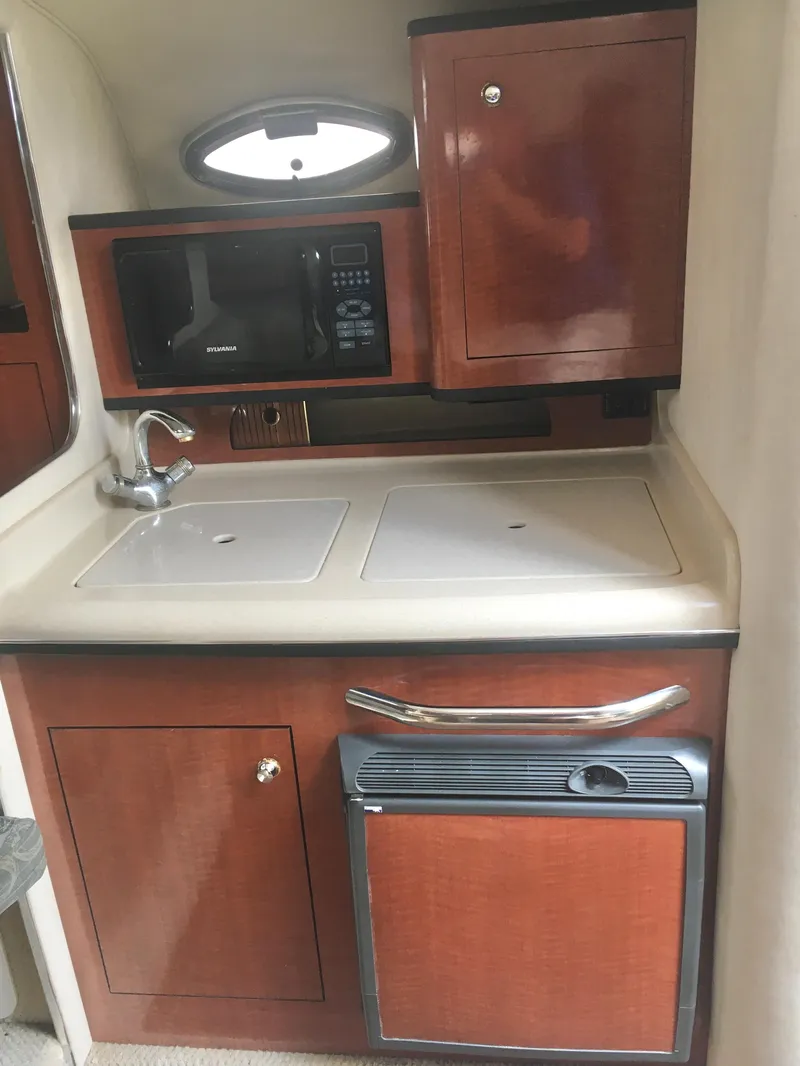 Slide: The Image of 2004 Sea Ray 280 Sundancer galley with microwave, sink, and storage cabinets. - 20