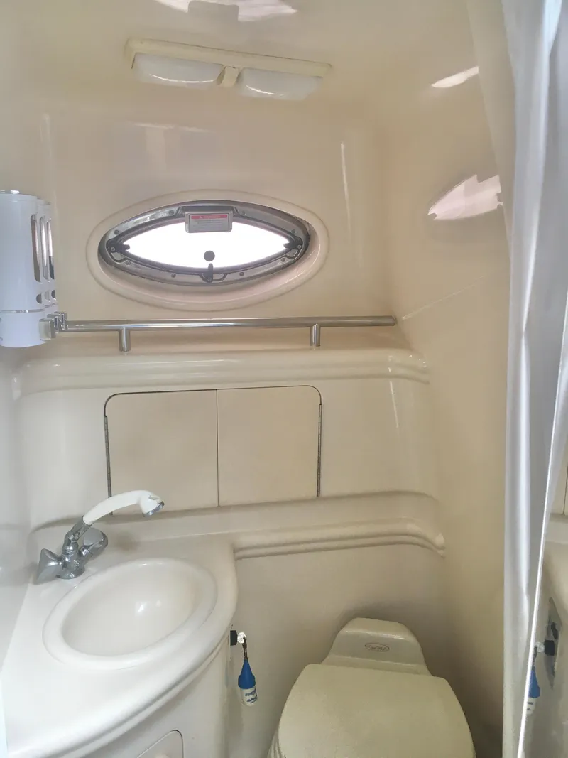 Slide: The Image of 2004 Sea Ray 280 Sundancer bathroom with sink, toilet, and porthole window. - 22