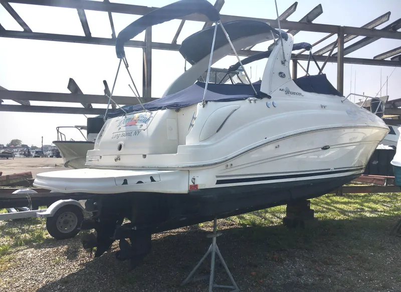 Slide: The Image of 2004 Sea Ray 280 Sundancer boat on dry dock, white hull, blue canopy. - 3