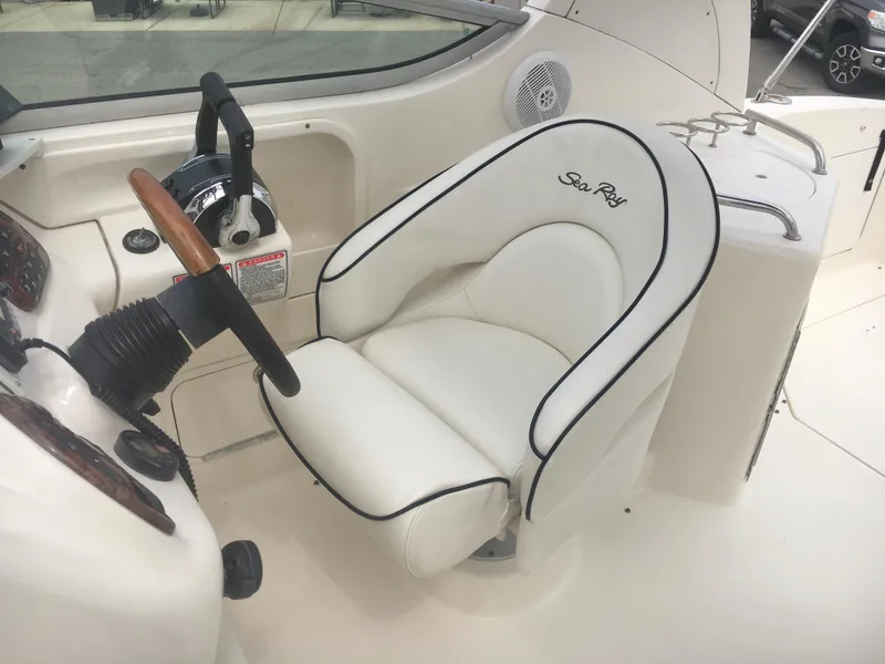 Slide: The Image of 2004 Sea Ray 280 Sundancer helm with white cushioned seat and steering controls. - 6