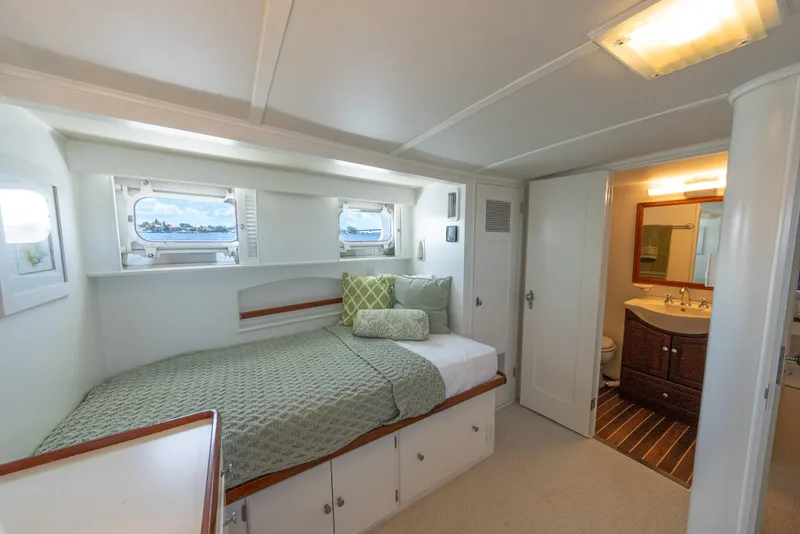 Slide: The Image of 1970 Trumpy houseboat bedroom with cozy bed, porthole windows, and adjacent bathroom. - 18