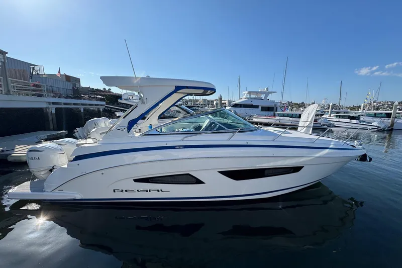 Slide: The Image of 2026 Regal 33 XO boat docked in marina, clear sky, calm water. - 0
