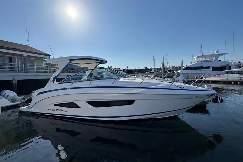 Slide: The Image of 2026 Regal 33 XO boat docked at marina under clear sky. - 10