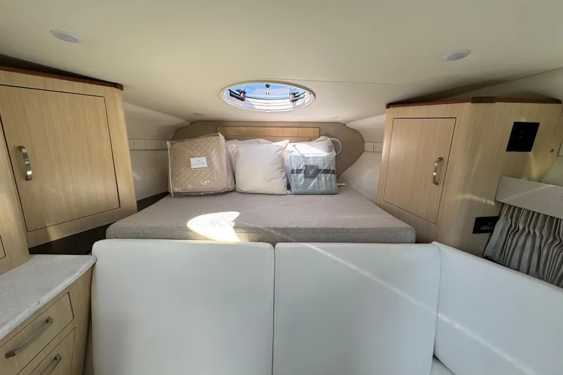 Slide: The Image of 2026 Regal 33 XO cabin interior with bed, wooden cabinets, and porthole window. - 113