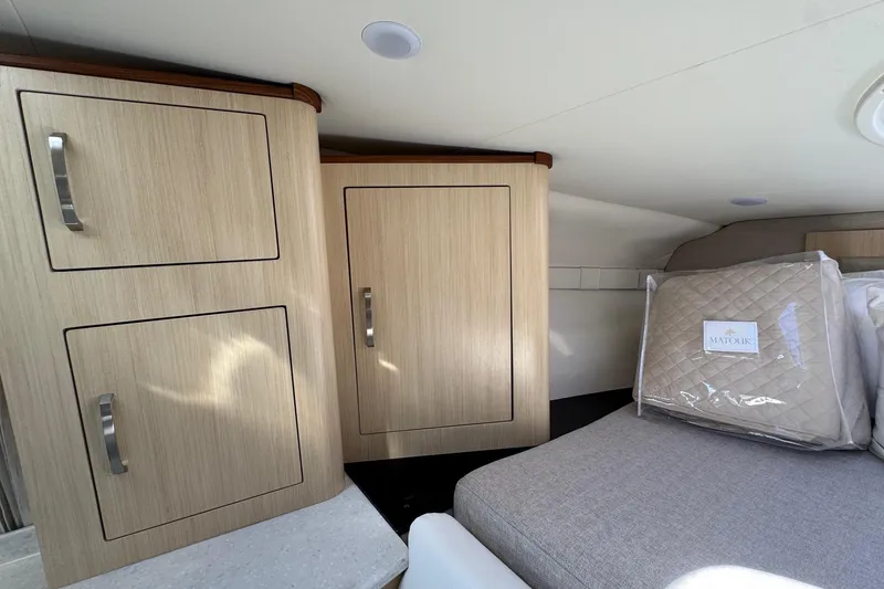 Slide: The Image of Interior of 2026 Regal 33 XO boat with wooden cabinets and cozy bedding. - 114