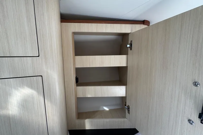 Slide: The Image of Open wooden cabinet with shelves inside a 2026 Regal 33 XO boat. - 115