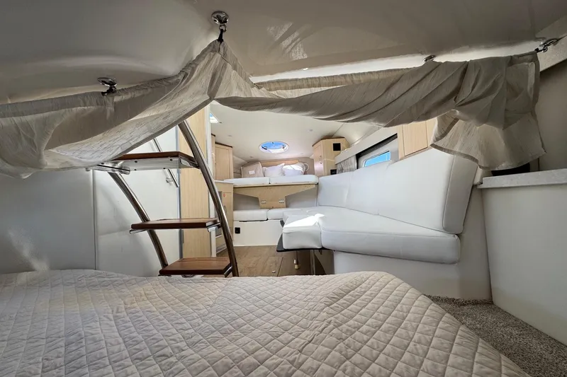 Slide: The Image of 2026 Regal 33 XO boat interior with cozy seating, bed, and wooden ladder. - 145