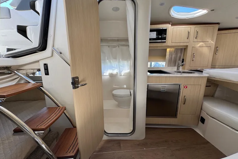 Slide: The Image of 2026 Regal 33 XO yacht interior with kitchenette, bathroom, and wooden stairs. - 146