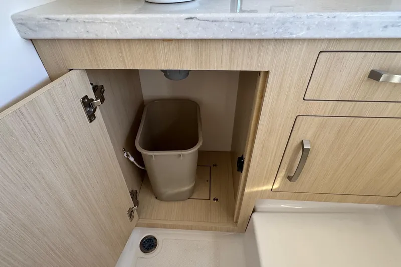 Slide: The Image of Cabinet with trash bin inside Regal 33 XO 2026 model, featuring light wood finish. - 152