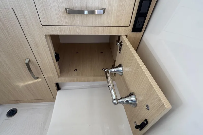 Slide: The Image of 2026 Regal 33 XO boat interior cabinet with open storage and sleek metal handles. - 155