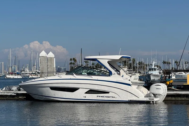 Slide: The Image of 2026 Regal 33 XO boat docked in marina, clear sky, calm water. - 2