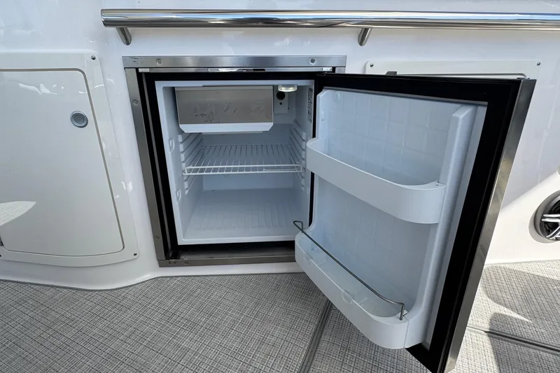 Slide: The Image of Open mini fridge on 2026 Regal 33 XO boat, showcasing interior storage space. - 49
