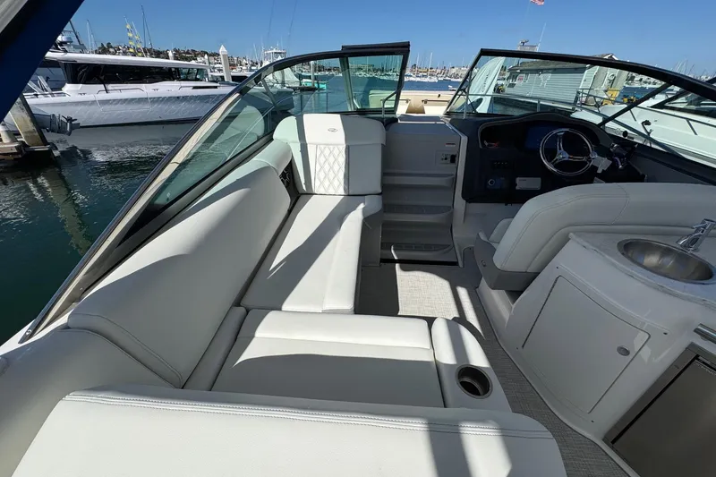 Slide: The Image of 2026 Regal 33 XO boat interior with white seating, steering wheel, and sink at marina. - 69
