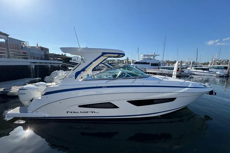 Slide: The Image of 2026 Regal 33 XO boat docked at marina, clear sky, calm water. - 7