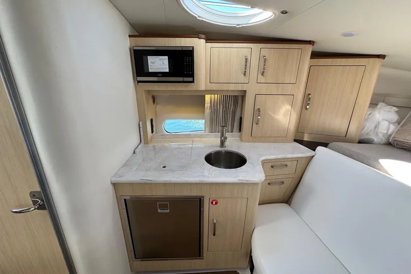 Slide: The Image of 2026 Regal 33 XO yacht interior kitchenette with microwave, sink, and storage cabinets. - 98