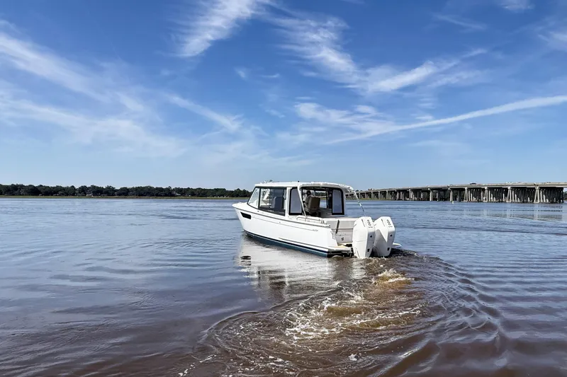 Slide: The Image of 2026 MJM 38x boat with beige seating and American flag at dock. - 12