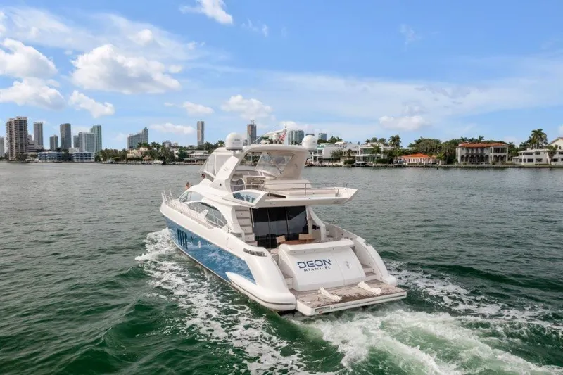 Slide: The Image of 2014 Azimut 64 Flybridge yacht cruising near city skyline and waterfront homes. - 11