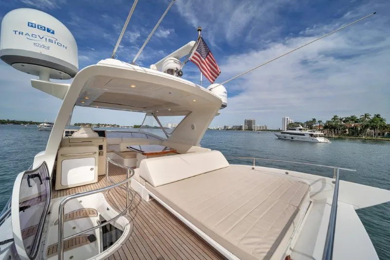 Slide: The Image of Azimut 64 Flybridge 2014 yacht with spacious deck, American flag, and scenic waterfront view. - 31