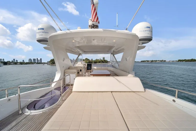 Slide: The Image of 2014 Azimut 64 Flybridge yacht with spacious deck, overlooking serene waters and city skyline. - 33