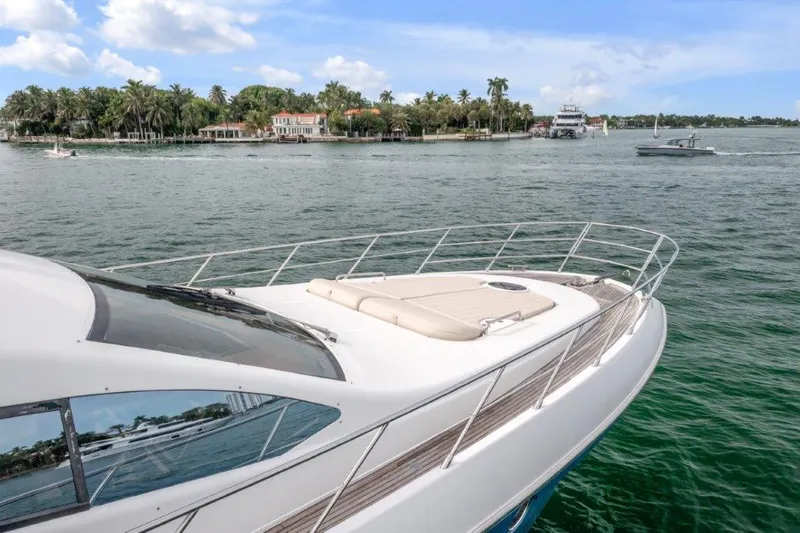 Slide: The Image of 2014 Azimut 64 Flybridge yacht cruising near a scenic shoreline. - 6