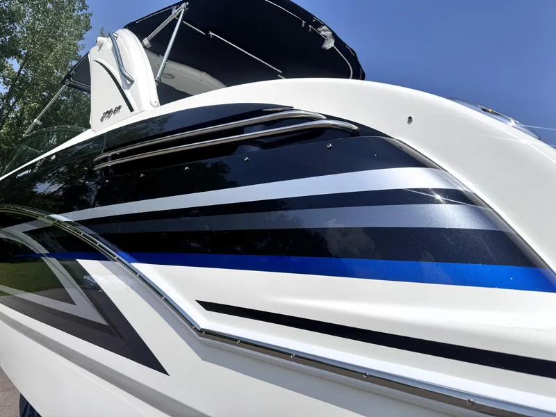 Slide: The Image of 2026 Formula 290 Bowrider boat with sleek black and blue stripes under a clear sky. - 16