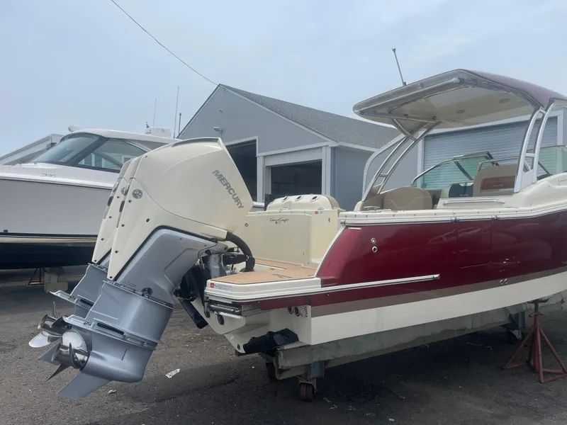 Slide: The Image of 2023 Chris-Craft Calypso 28 boat with outboard motor, docked near a building. - 11