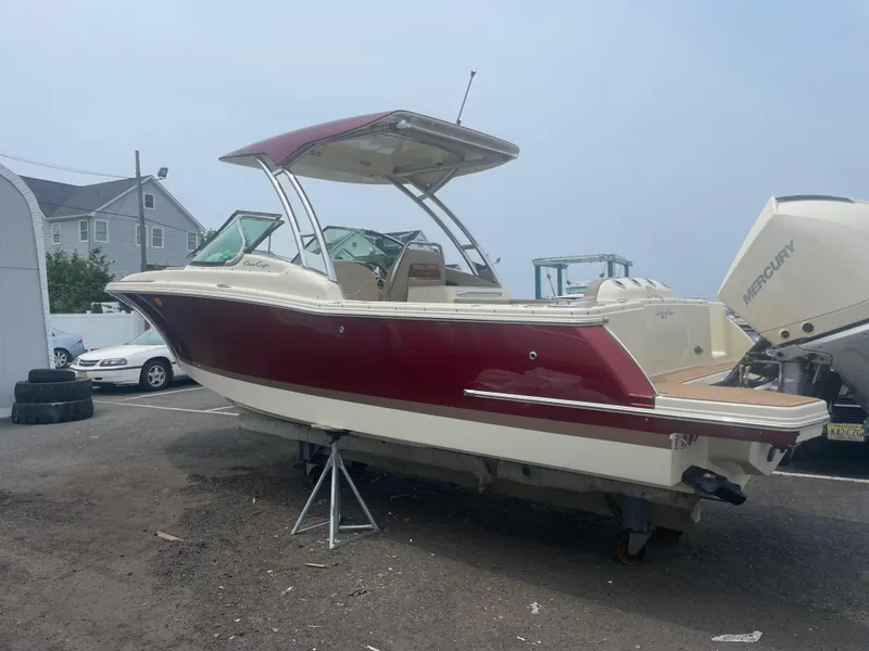 Slide: The Image of 2023 Chris-Craft Calypso 28 boat with red and white exterior, parked on a stand. - 12