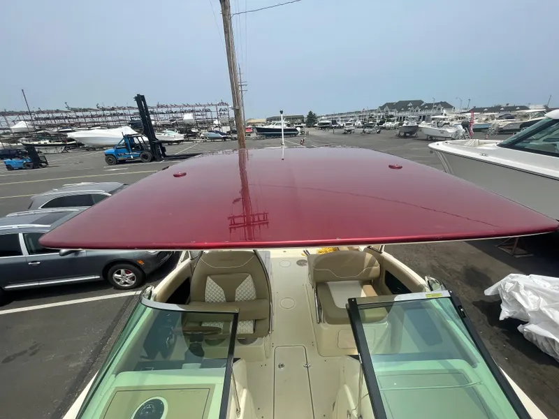 Slide: The Image of 2023 Chris-Craft Calypso 28 with red canopy, parked in a marina. - 43