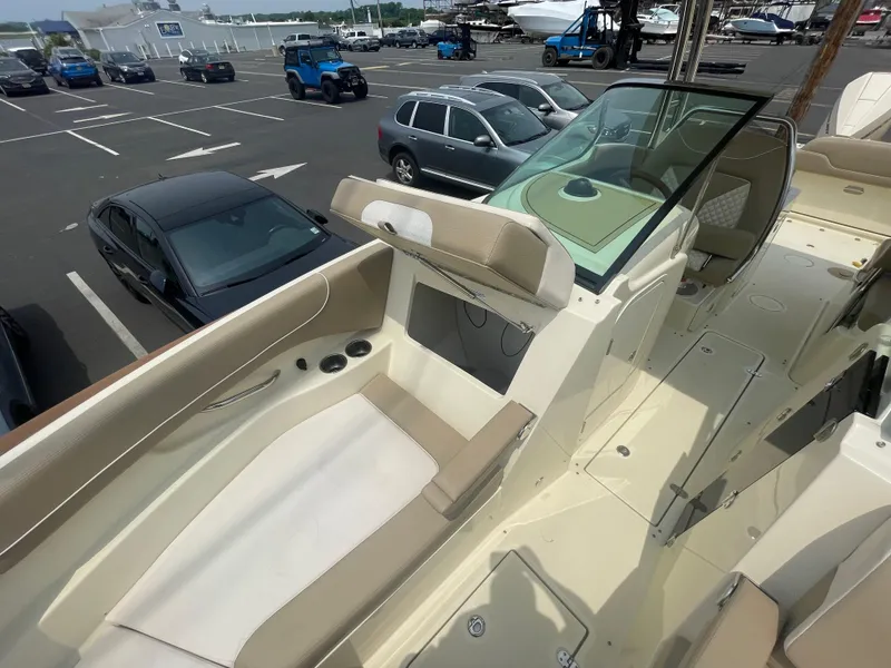 Slide: The Image of 2023 Chris-Craft Calypso 28 boat interior with beige seating and windshield, parked in a lot. - 47