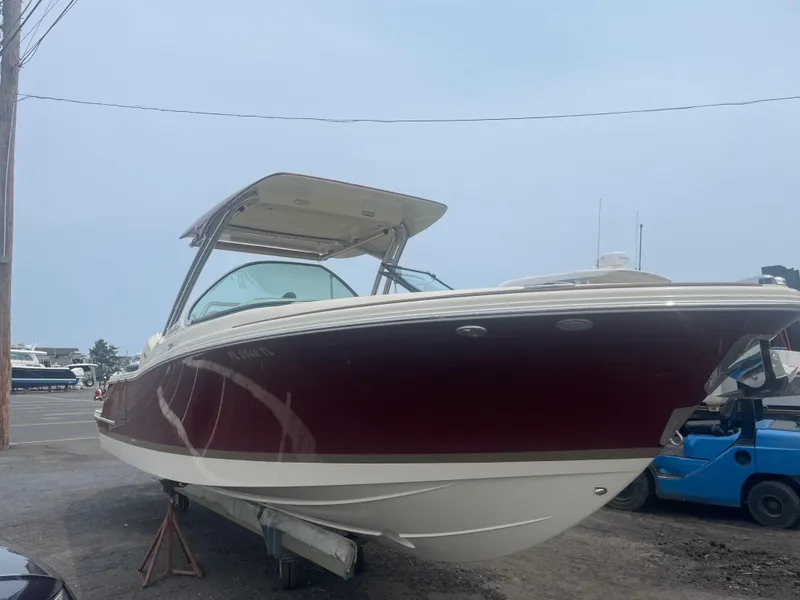 Slide: The Image of 2023 Chris-Craft Calypso 28 boat with red hull on display outdoors. - 56