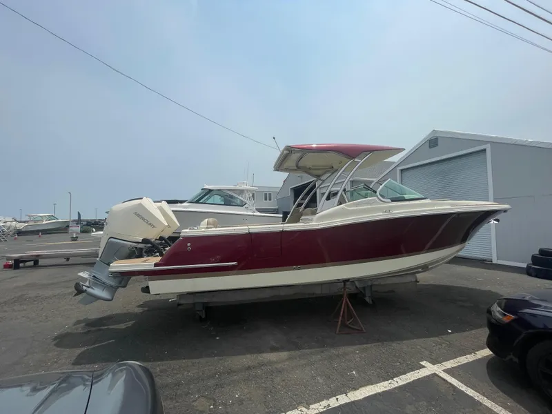 Slide: The Image of 2023 Chris-Craft Calypso 28 boat with red hull, parked outdoors. - 57