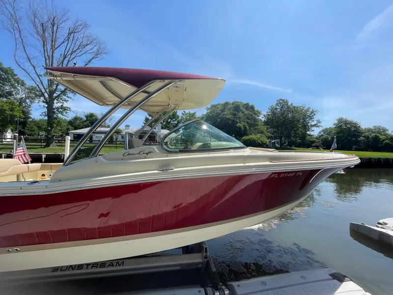 Slide: The Image of 2023 Chris-Craft Calypso 28 boat docked on a sunny day, featuring a red and white design. - 7