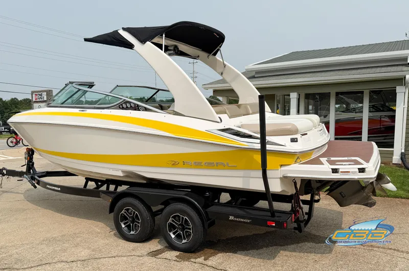 Slide: The Image of 2010 Regal 2300 Bowrider boat with yellow accents on a trailer, parked outdoors. - 2