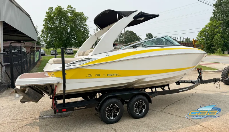Slide: The Image of 2010 Regal 2300 Bowrider boat on trailer, yellow and white design, parked outdoors. - 4