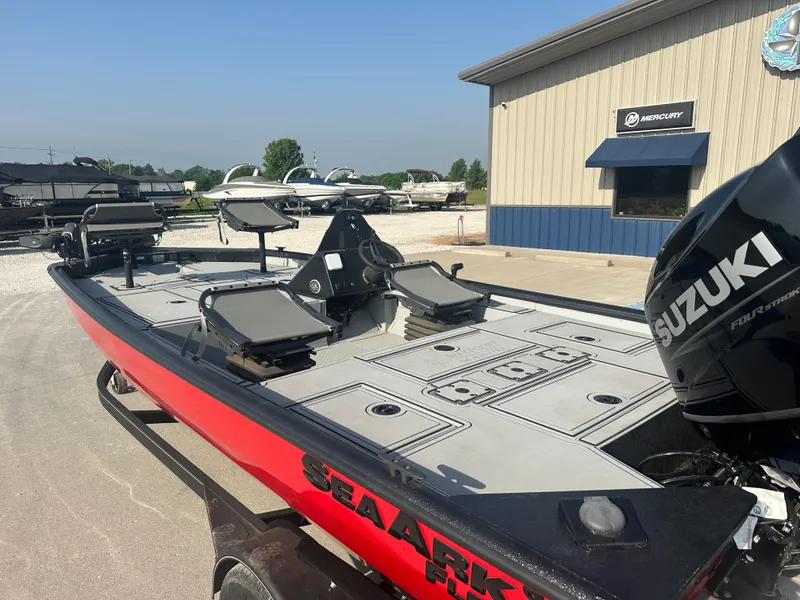 Slide: The Image of 2025 SeaArk Flex 19 boat in red and black on a trailer, parked outdoors. - 2