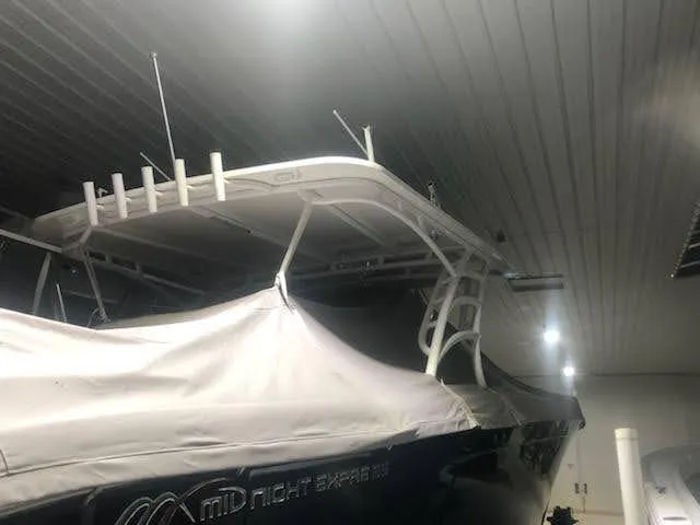 Slide: The Image of 2019 Midnight Express 39 Cuddy boat in storage, partially covered, with visible T-top and antennas. - 17