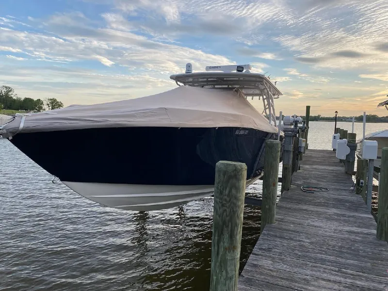 Slide: The Image of 2019 Midnight Express 39 Cuddy boat docked, covered, under a cloudy sky. - 21