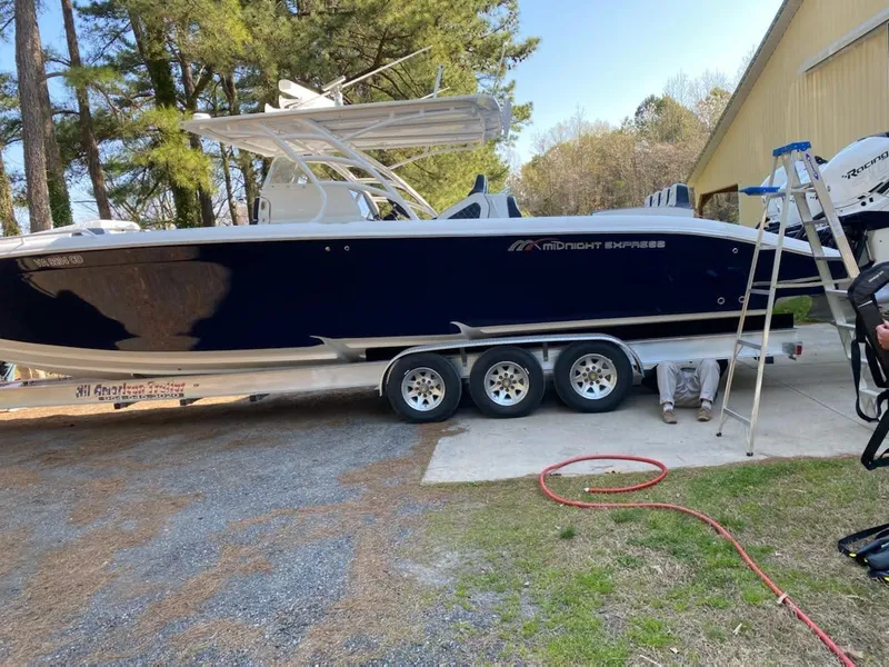 Slide: The Image of 2019 Midnight Express 39 Cuddy boat on trailer, parked outdoors near trees and building. - 24