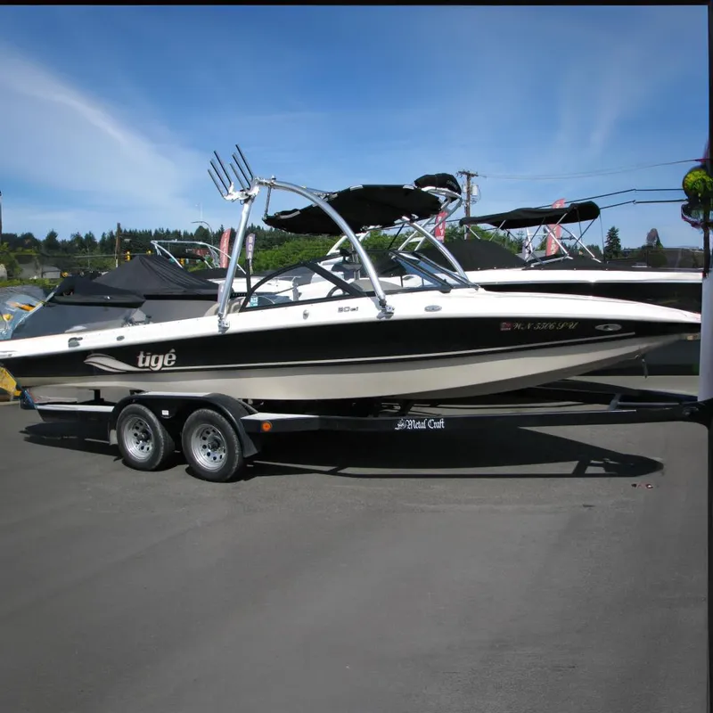 The Image of 2001 Tigé 20ci boat on trailer, black and white design, parked outdoors. - 0