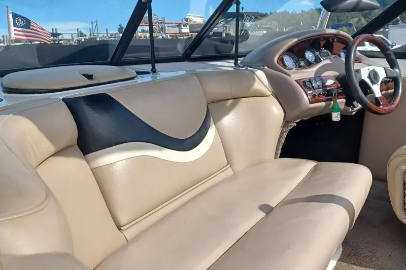 Slide: The Image of 2001 Tigé 20ci boat interior with beige seating and dashboard, American flag in background. - 9