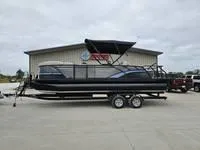 The Image of 2025 Sylvan L-3 DLZ pontoon boat on trailer, parked outside a building. - 0