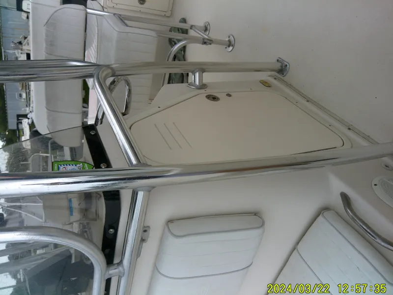 Slide: The Image of 2007 Cobia 214 CC boat interior with seating and storage, docked near a building. - 4