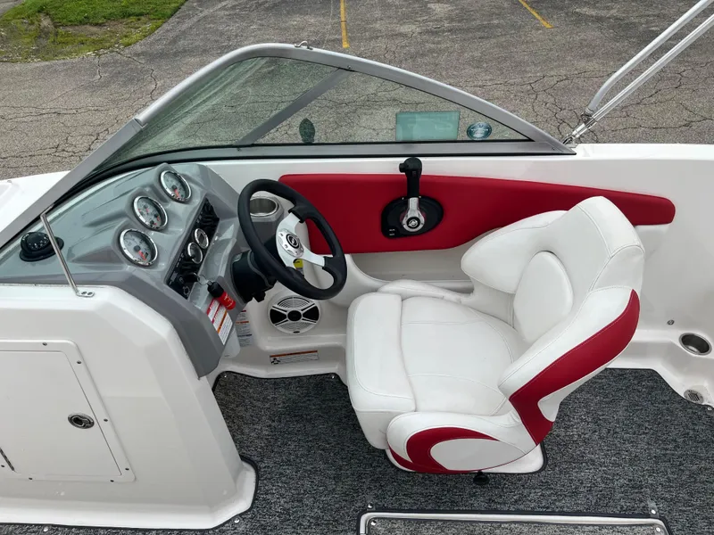Slide: The Image of 2014 Chaparral 19 Sport H2O boat interior with white and red seating, dashboard, and steering wheel. - 10